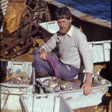 A. Každailis ant VŽT-4389 „Kalvarija“ denio prie preparavimui atrinktų moliuskų, kurių kriauklės papildys jūrų faunos rinkinius. 1975 m. gegužė. Nuotraukos autorius Eugenijus Buivydas. Lietuvos jūrų muziejus